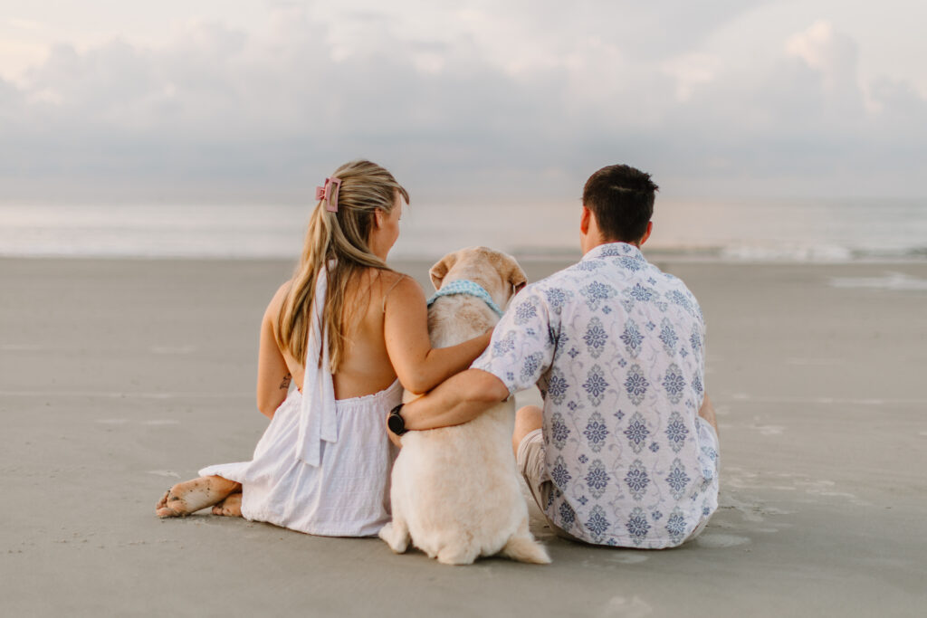 Dog and its owners sitting on the beach